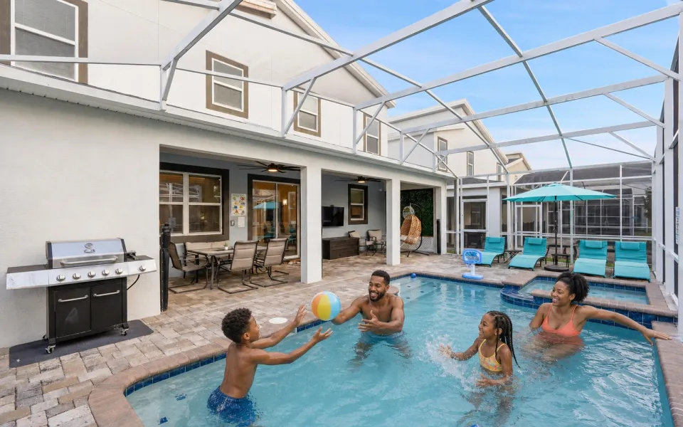 Family of four playing with a beach ball in the private screened pool at 690 Drop Shot Drive